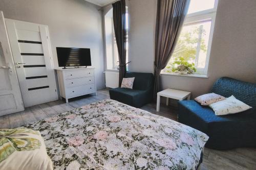 ein Schlafzimmer mit einem Bett, einem TV und einem Sofa in der Unterkunft Kamienica Slowackiego in Duszniki-Zdrój