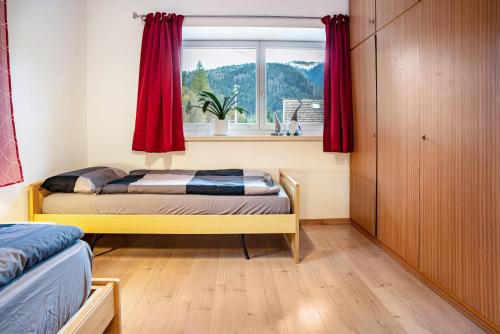 a bedroom with two beds and a window with red curtains at Martina's Place in Castello di Fiemme