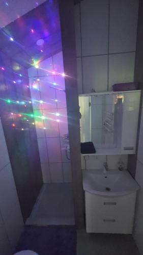a bathroom with a sink and lights on the wall at Violetinis namelis/ Sodyba Geras in Anykščiai