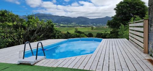 a swimming pool on a wooden deck with mountains in the background at Casa Vista do Monte in Povoação