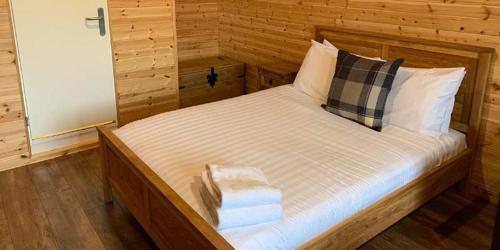 um quarto com uma cama grande e paredes de madeira em Superior Glamping Pod with Hot Tub em Frodsham
