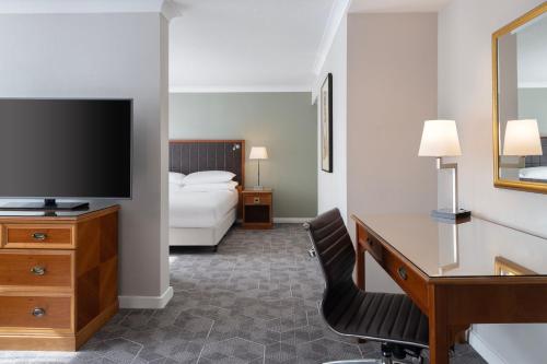 a hotel room with a bed and a desk and a television at Delta Hotels by Marriott Heathrow Windsor in Windsor