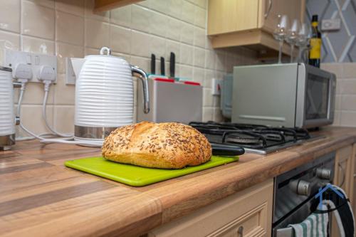a loaf of bread on a cutting board on a kitchen counter at Garfield House, 3 bed house, sleeps 7, Nr Rushden Lakes, allocated parking, corporates welcome in Wellingborough
