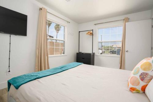 a bedroom with a large bed and two windows at Stylish 4BR Home near Disneyland wParking in Midway City