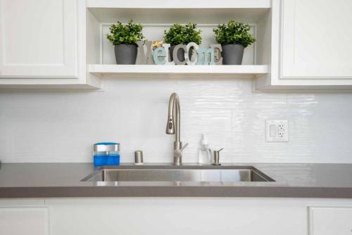 a kitchen sink with potted plants on a shelf at Stylish 4BR Home near Disneyland wParking in Midway City