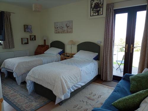 a bedroom with two beds and a couch at Cowslip Corner Room with Sea View in Broad Haven