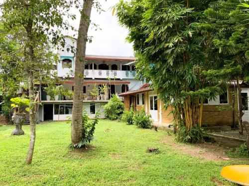 a house in the middle of a yard with trees at Chill River Villa - Villa with Scenic River Views in Weligama