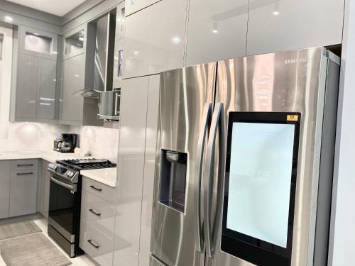 a kitchen with a stainless steel refrigerator with a screen on it at Modern and New house near PNE with Big Garden and Free Parking in Vancouver