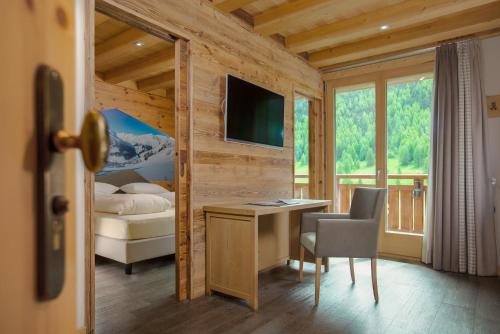 a bedroom with a desk and a bed and a television at Hotel Amerikan in Livigno