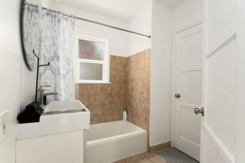 a white bathroom with a sink and a bath tub at Centrally Located 2BR Home near LAX SoFi Stadium in Inglewood