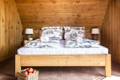 a bed with two pillows and a basket of apples at Domki Fox House z jacuzzi elektrycznym na wyłączność in Kościelisko