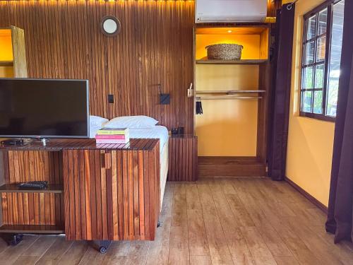 a bedroom with a bed and a desk with a television at Jan Kok Lodges in Willibrordus
