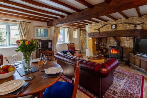 uma sala de estar com uma mesa e uma lareira em Graziers Cottage - character Cotswold cottage with inglenook, parking and pub nearby em Cheltenham