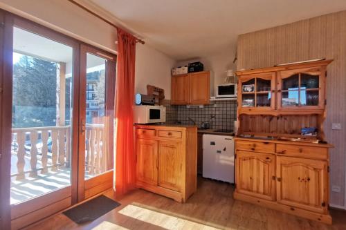 cocina con armarios de madera y balcón en Appartement 4 personnes au pied des pistes, en Les Déserts