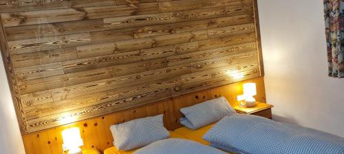 a bedroom with a wooden wall and a bed with two pillows at Landhaus Eibelesee in Oberstaufen