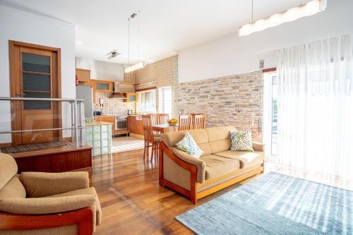 a living room with a couch and chairs and a kitchen at 8 Rodrigues Family House - Villa with patio in Nazaré
