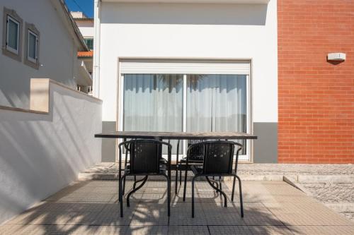 a table and chairs on a patio with a window at 8 Rodrigues Family House - Villa with patio in Nazaré