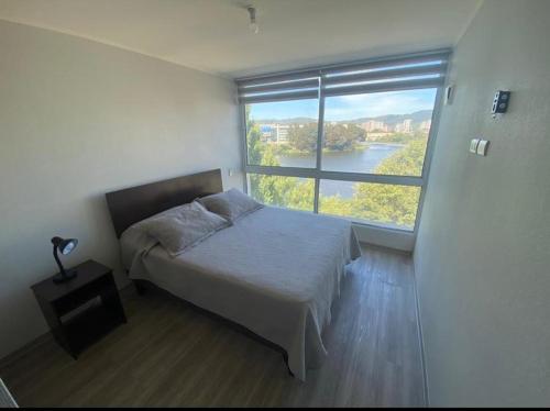 1 dormitorio con cama y ventana grande en Departamento Full Concepcion, en Concepción