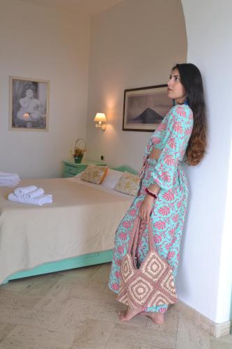 a woman in a dress standing next to a bed at Hotel Ossidiana Stromboli Center in Stromboli