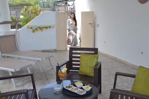 a woman standing on a patio with a table and chairs at Hotel Ossidiana Stromboli Center in Stromboli