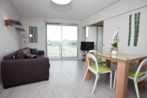 a living room with a table and chairs and a couch at Résidence Le Crystal Dinard Plage in Dinard