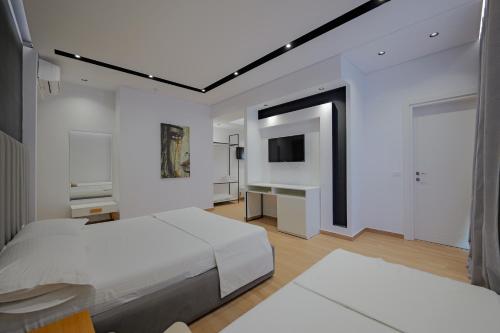 a bedroom with two beds and a flat screen tv at Sea & Sand Hotel in Vlorë