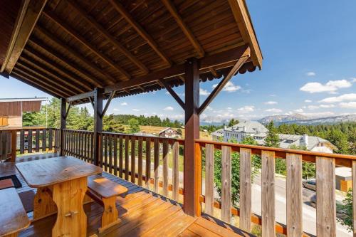 a wooden deck with a table and bench on a balcony at Chalet Les étoiles vue Mont Blanc in Pugny-Chatenod