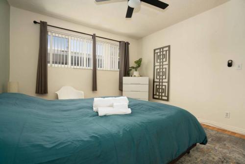 1 dormitorio con 1 cama azul y 2 toallas blancas en Amazing 3BR Home near Hollywood DTLA, en Los Ángeles