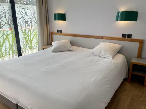 - une chambre avec un lit blanc et 2 oreillers dans l'établissement Le Keréden - Breizh Ecolodge Hôtel, à Locarn
