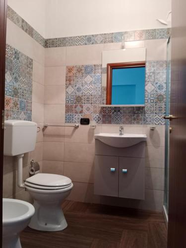 uma casa de banho com um WC, um lavatório e um espelho. em Trotskyhouse em Campobello di Licata