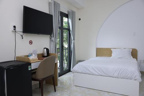 a bedroom with a bed and a desk with a computer at Arina Luxury Hotel - Vincom Tay Ninh in Tây Ninh
