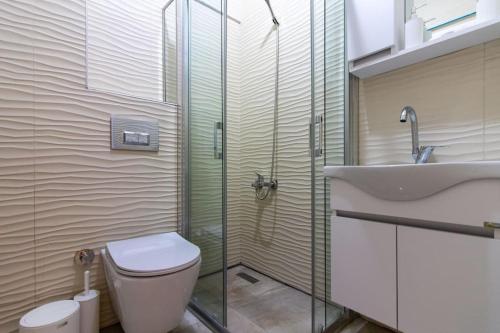 een badkamer met een douche, een toilet en een wastafel bij Cosmopolitan & Stylish 1BR Apartment/Central Şişli in Istanbul