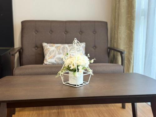 StayInn Getway MyHome Private Hotel-style Apartment في كوتشينغ: إناء من الزهور على طاولة قهوة مع أريكة