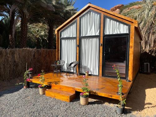 una pequeña casa de madera con mesa y sillas en منتجع ريف العلا, en Al Ula