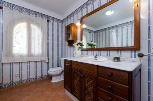 een badkamer met een wastafel, een toilet en een spiegel bij Villa Son Tugores in Lloseta