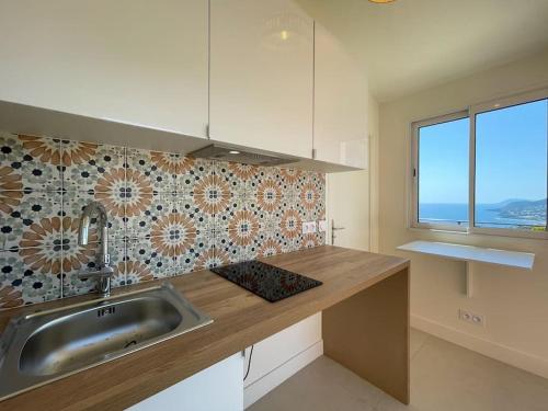 a kitchen with a sink and a counter with a window at Villa Terracotta - Stunning Sea View & Pool in Carqueiranne