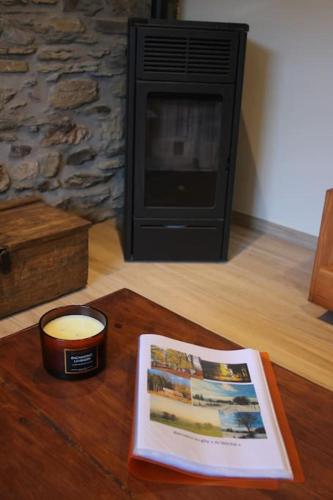 a candle and a book on a table with a fireplace at Gîte champêtre Al Wèrihè in Lierneux