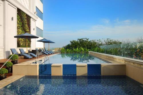 a swimming pool in a building with chairs and umbrellas at Four Points by Sheraton Medan in Medan