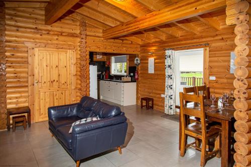 a living room with a leather couch and a table at Teal Lodge - Nordic Log Cabin with private hot tub in Selby