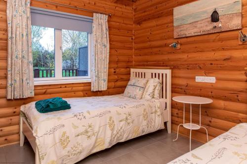 a bedroom with a bed and a window in a log cabin at Teal Lodge - Nordic Log Cabin with private hot tub in Selby