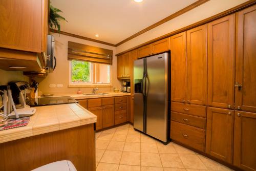 a kitchen with wooden cabinets and a stainless steel refrigerator at Stay In CR Los Sueños Condos in Jacó