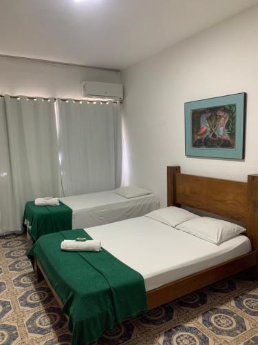 twee bedden in een kamer met groene lakens bij Pousada Olívia in São Pedro da Aldeia