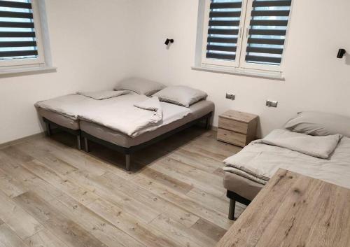 2 camas num quarto com pisos e janelas em madeira em Dom gościnny 4 JAWA II em Tuczempy