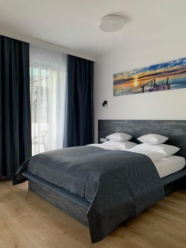 アウグストゥフにあるREMAR - Apartamentai prie Biale Ežeroの大きなベッド付きのベッドルーム1室、壁に絵画が飾られています。