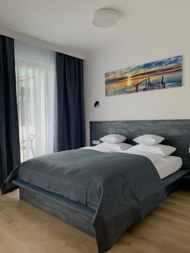 a bedroom with a large bed and a painting on the wall at REMAR - Apartamentai prie Biale Ežero in Augustów