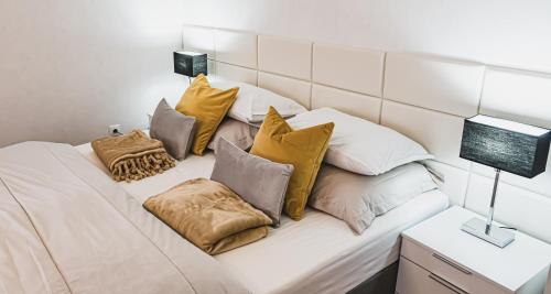 a couch with many pillows on it with a television at Rosegarden Apartman in Sárospatak