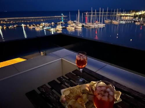 a glass of wine on a table with a view of a marina at Ortigia D'aMare Apartment in Siracusa