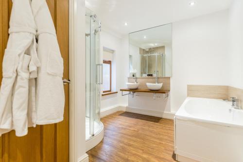 a white bathroom with two sinks and a mirror at The Gower Hotel in Swansea