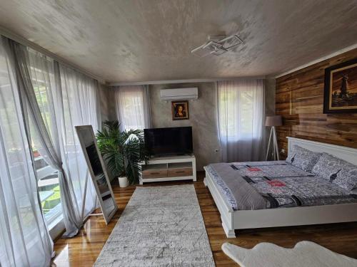 a bedroom with a bed and a flat screen tv at Апартамент за гости Боляри in Velingrad