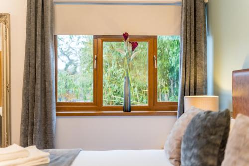 a bedroom with a window with a flower in a vase at The Gower Hotel in Swansea